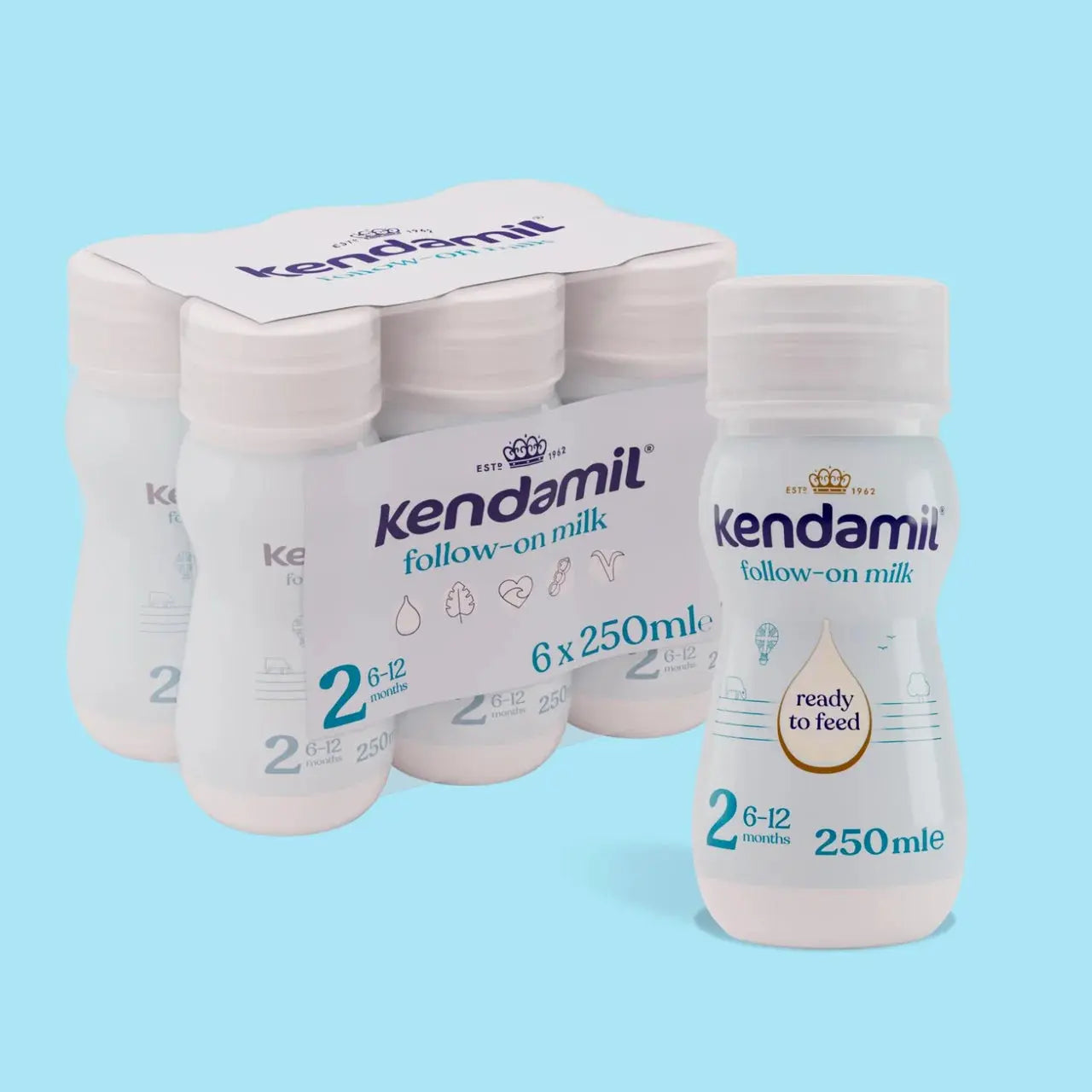 A pack of Kendamil follow-on milk bottles, with one bottle in the foreground and five more in the background inside a cardboard carrier, set against a solid light blue background.