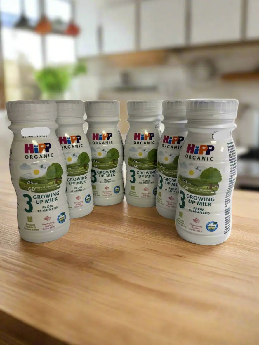 Six bottles of HiPP Organic Growing Up Milk on a wooden kitchen counter