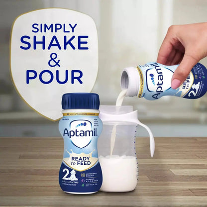 Aptamil Ready to Feed bottle and container with text 'Simply Shake & Pour' on a wooden surface.