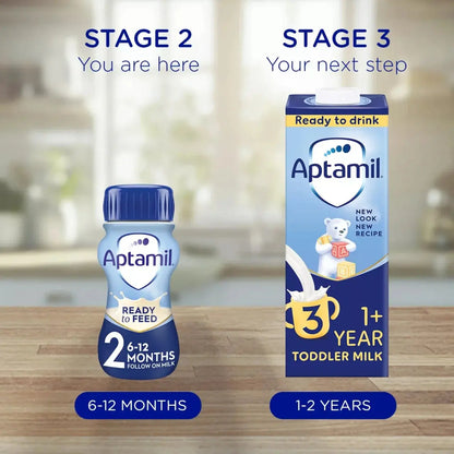 Aptamil bottle and carton on a wooden surface with a blurred kitchen background