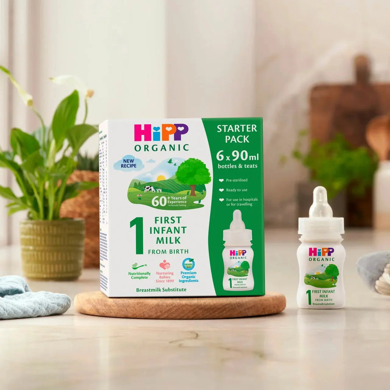 HiPP Organic First Infant Milk starter pack and bottle on a wooden surface with a blurred background